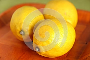 Still life with three ripe yellow lemons on brown tray