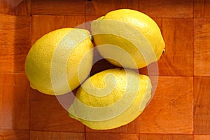 Still life with three ripe yellow lemons on brown tray