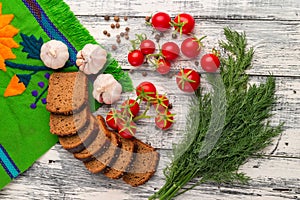 Still life of tomatoes, black bread, garlic, fennel, and pepper