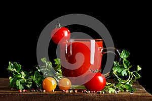 Still life with tomatoes, parsley, garlic and tomato juice on wooden boards. On a black background.