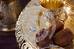 Still life with traditional golden arabic coffee set with dallah, coffee pot jezva, cup and dates. Dark background.