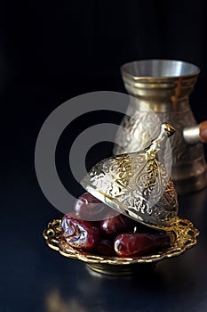 Still life with traditional luxury golden arabic coffee set with jezva, cup and dates. Dark background. Ramadan concept