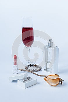 A still life with a transparent perfume bottle, a faded rose, a bracelet, a lipstick, a box with the silver earrings