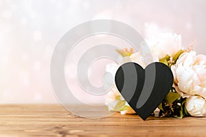 Still life Valentines day festive background with empty black chalkboard heart on wooden background. Mockup with copy