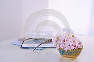 still life vase flowers, an open book, reading glasses, on white table