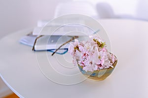 still life vase flowers, an open book, reading glasses, on white table