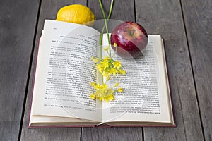 Still life of vintage book with yellow freesia, apple, lemon on