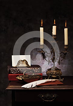 Still life with vintage books, bronze candlestick, Feather pen, envelopes and press papier.