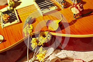 Still life with a vintage electric guitar, dried flowers and old music notes closeup