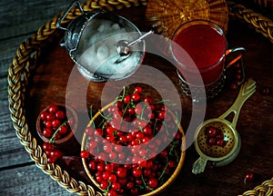 Still life in vintage style. Close up wood bowl with red current berry and glass with tea or fruit-drink. Top view