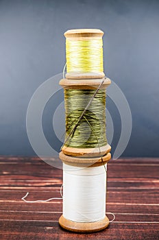 Still life of vintage wooden spool thread with needle on wooden