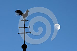 Still life of weathercock and moon in blue sky