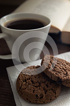 Still life. White cup with coffee and cookies in front of an open book with poetry