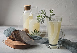 Still life with white kvass or sourdough in bottles and glass with slices of rye bread