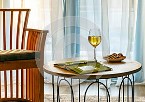 Still life with white wine and a book on a coffee table against the background of a window