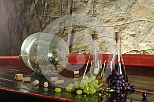 Still life with wine glasses, wine bottles and grapes in old cellar