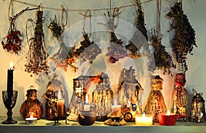 Still life with witch bottles, burning candles, healing herbs and flowers