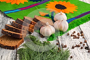 Still life on wooden background: black bread, garlic, fennel, ba