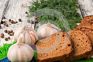 Still life on wooden background: black bread, garlic, fennel, pe