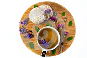 Still life on a wooden board. A cup of herbal tea, biscuits and wildflowers. White background.