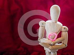 Still life wooden puppet and pink heart.