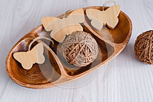 Still life of a wooden salad bowl of three sections, wooden decorative butterflies and wooden decor on a wooden background.