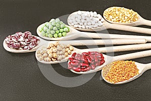 Still life of wooden spoons, each one filled with a variety of colorful beans and jelly beans