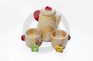 Still life of the wooden teapot and tow cups, on white background. Wooden kids toys.