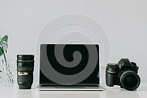 Still life working from home desk with professional photographic equipment, camera, lens, computer monitor, electronics indoors