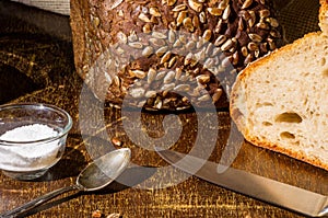Still life - yeast-free buckwheat bread, black bread with sunflower seeds, coarse salt in glass jar, a knife, and a