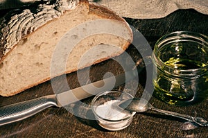 Still life - yeast-free buckwheat bread with olive oil and coarse salt in glass jars, a knife, and a linen napkin on a