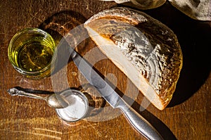 Still life - yeast-free buckwheat bread with olive oil and coarse salt in glass jars, a knife, and a linen napkin on a