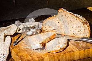 Still life - yeast-free buckwheat bread with sliced pieces, and coarse salt in a glass jar, a knife, and a linen napkin