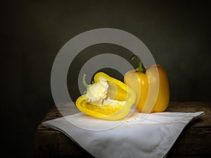 Still life with yellow peppers, one cut, chiaroscuro. photo