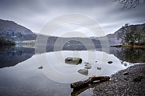 A still and misty morning shot of Lake Buttermere shoreside.