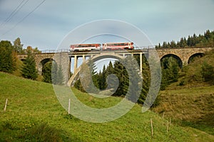 Old train passing on the old railway viaduct with modern center part over the valley in the mountains, Slovakia