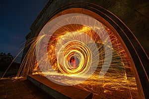 Still wool fire show under old arch in the night.