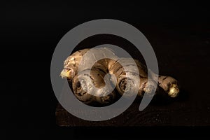 Stillife of a ginger root on a wooden table against a dark background