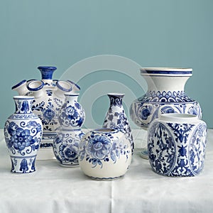 Stillife of natural light and old Dutch Delft blue lidded vases  in the background on white blue linen against a blue background