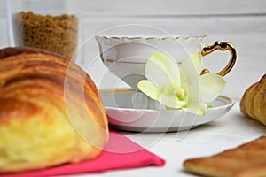 Stilllife of coffee cup with espresso, croissants, biscuits, tender flower, brown sugar on a wooden background