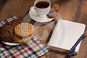 Stilllife with a notebook and cookies on the wooden table