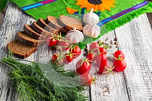 Stilllife on wooden background: tomatoes, black bread, garlic, f