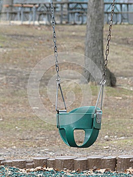 An Empty Green Kiddie Swing in a Park or Playground photo