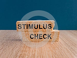 Stimulus CheckConcept. Words Stimulus Check on brick blocks. Beautiful wooden table, dark blue background. Copy space. Coronavirus