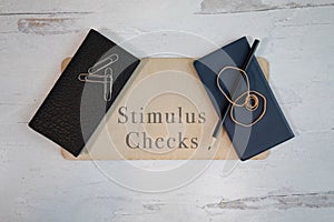 Stimulus checks painted on wood sign with check books framing