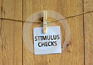 Stimulus checks symbol. White paper with words `Stimulus checks`, clip on wooden clothespin. Beautiful wooden background. Busine