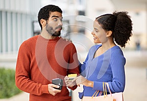 Stingy Husband Giving Credit Card To Wife Shopping Outdoor