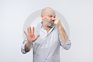 Stinky smell mature man in shirt holding nose