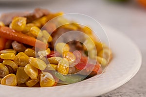 Stir the corn and carrots, put the pork on the plate on the wooden plate