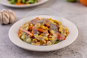 Stir the corn and carrots, put the pork on the plate on the wooden plate